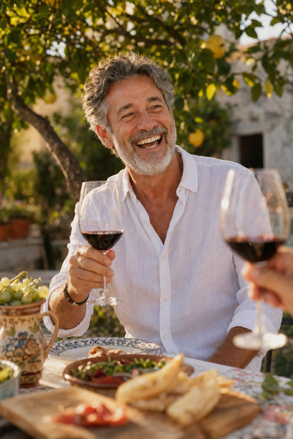 Man laughing genuinely at a sunlit Mediterranean lunch table