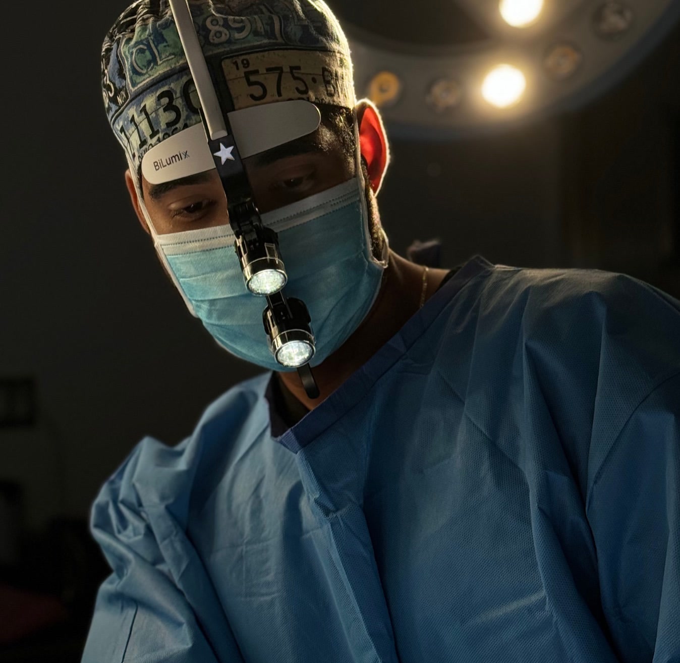 Dr. Luis Monta&ntilde;o in surgical scrubs and loupes during a facial procedure