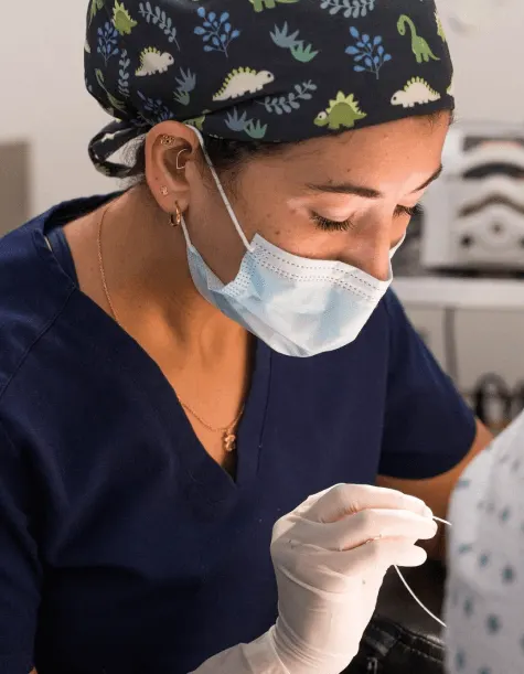 Gloved hands placing a titanium dental implant during a full-arch case at the partner clinic in Tijuana.