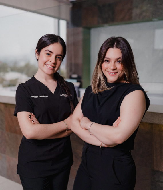 Two Allure RT MX clinicians in branded scrubs, smiling with arms crossed inside the Tijuana clinic.